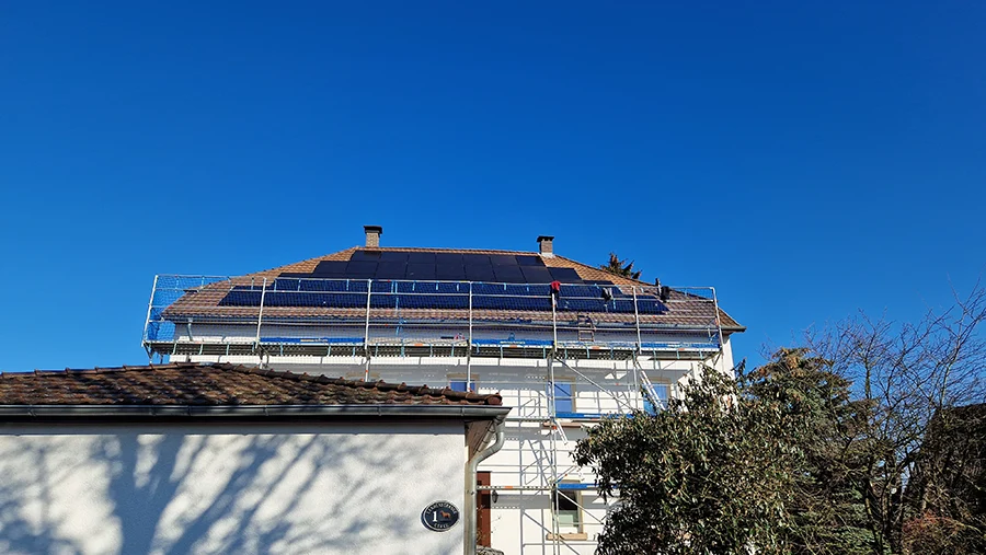 Installation von Solaranlagen auf einem Hausdach unter blauem Himmel