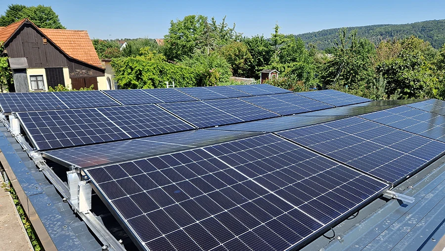 Solaranlage auf einem Hausdach an einem sonnigen Tag mit grfcner Umgebung